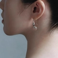 Eleganti orecchini in metallo liquido argento con sfera di cristallo su una modella - Orecchini a zucca