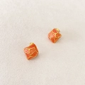 Dettaglio di orecchini a cubo geometrici con smalto arancione e bordi in metallo dorato - Arancione