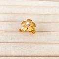 Ethno-Goldring in Blumenform mit gebürsteter Textur und Perle auf weißem Stoffhintergrund - US 8 / Goldener Ring