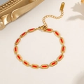 Detailed close-up of gold titanium steel bracelet with red oval enamel charms and clasp - Gold Color Red