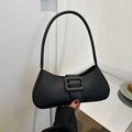 Borsa baguette minimalista in pelle nera opaca con fibbia su un tavolo da caffè - Nero
