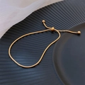 Vintage adjustable gold snake chain anklet in stainless steel on black textured plate - Gold