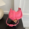 Pink crescent underarm bag with knotted strap and small pouch held by a model - Rose Pink