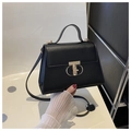 Detail of black leather handbag featuring a prominent gold T-shaped rotating metal clasp - Black
