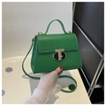 Close-up of green leather handbag featuring a golden T-shaped metal twist lock and top handle - Green