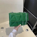 Modern green quilted crossbody bag with silver chain strap held by hand in a minimalist setting - Green