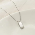 Macro shot of a minimalist silver rectangular pendant necklace on a satin silk background - Large Gold Bar Style (XL2097) / Steel