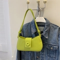 Detail of lime green underarm bag with knot strap and round buckle against denim - Green