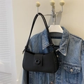 Close-up of minimalist black matte crescent shoulder bag with unique ring buckle and knotted strap - Black