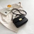 Classic black leather crossbody bag with golden geometric lock on a beige blazer - Black
