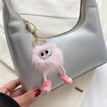 Pink plush monster keychain with big eyes and white legs on a silver shoulder bag - Pink Monster Pendant