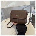 Detailed close-up of dark brown PU leather saddle bag with Fashion Trend printed text - Brown