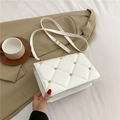White quilted crossbody bag with gold rivet studs on a soft cream fabric background - White