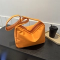Bolso tote de nylon naranja brillante con hebilla plateada ajustable sobre madera - Naranja