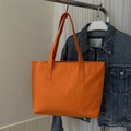 Detail of orange quilted tote bag with V-shaped stitching hanging in casual setting - Orange Upright Chevron