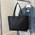 Dettaglio di borsa tote nera con trapuntatura a V appesa a un supporto in metallo - Nero Chevron Invertito