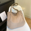 Grande borsa tote in tela kaki con ampia tracolla esposta su una sedia minimalista - Cachi