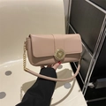 Elegant beige crossbody bag with gold floral buckle and chain strap shown in hand - Khaki