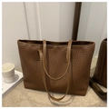 Close-up of brown woven texture and slim handles on a large commuter tote bag - Brown
