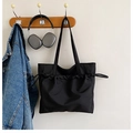 Detail of black waterproof nylon tote bag with drawstring texture in a lifestyle setting - Black