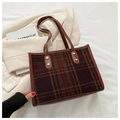 Close-up of vintage plaid tote bag with leather straps and gold rivet detailing - Brown