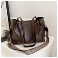 Close-up of deep brown leather tote bag with woven shoulder strap and fashion logo - Brown