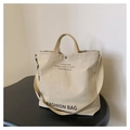 Nahaufnahme der cremefarbenen Canvas-Tasche mit schwarzem Aufdruck und Trageriemen - Khaki