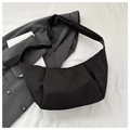 Close-up of minimalist black nylon crescent bag with adjustable wide strap on white fabric - Black
