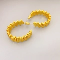 Detalle macro de pendientes de aro bañados en oro con una textura geométrica dentada - En forma de C / Dorado