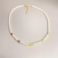 Minimalist pearl necklace with colorful beads and gold lobster clasp on grey background - Multicolor Accented Pearl Necklace