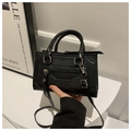 Close-up of stylish black crossbody bag featuring silver hardware and tassel detailing - Black