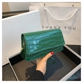 Detailed macro of dark green crocodile texture on a small glossy flap shoulder bag - Green