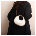 Detail of white woven crescent bag with brown leather trim worn by a model - White