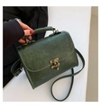 Close-up of vintage dark green crossbody bag with embossed floral pattern and bronze clasp - Green
