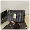 Detail of black quilted leather shoulder bag featuring golden chain and twist lock clasp - Black