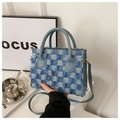 Detailed close-up of blue and white checkered denim bag with fringe edges and metal D-ring - Blue