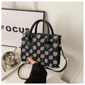 Macro detail of checkered tweed handbag with fringed edges and leather handles - Black