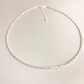 Collana minimalista a corda argentata con chiusura regolabile su uno sfondo grigio - Argento