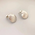 Makro-Detail des muschelförmigen Silberohrrings mit einem funkelnden Zirkonia-Stein - Weißgold