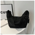 Detail view of a black crescent nylon tote bag with wide strap and woven knot zipper pull - Black