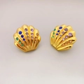 Goldene Muschelohrringe mit bunten Kristallen und Vintage-Texturen auf grauem Grund - Goldene Strass Muschel Ohrstecker