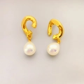 Détails de boucles d'oreilles dorées avec perles blanches en goutte et reflets irisés - Or