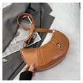 Detailed macro view of the brown crescent bag's textured leather and silver metal hook - Brown
