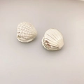 Close-up of scallop shell earrings featuring one cubic zirconia paved and one polished silver surface - White Gold