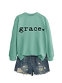 Detail of mint green sweatshirt with grace print paired with distressed denim shorts - Light Green Sweatshirt (Black Font)