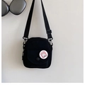 Detail of black mini canvas crossbody bag with magnetic front pocket and cartoon badge - Black