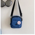 Detail of blue canvas mini crossbody phone bag with adjustable strap and cartoon badge - Blue
