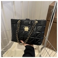 Close-up of black quilted leather tote bag with gold chain strap and metal buckle - Black