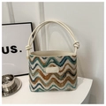 Detail of wavy knit texture and leather brand label on a colorful striped bucket bag - White