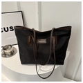 Detalle del bolso tote de nailon negro con asas de cuero marrón y parche de logo - Negro y Marrón